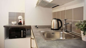 A modern kitchen with a built-in microwave, stainless steel sink, and a kettle. - 101 - Studio confortable avec kitchenette Paris 5 (Paris)