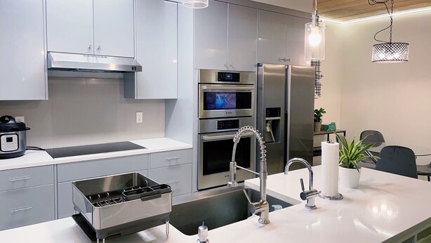 A modern kitchen with stainless steel appliances, a built-in oven, a sink with a faucet, and pendant lighting.