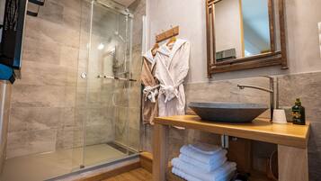 Une salle de bain moderne avec une douche à l’italienne en verre, un meuble-lavabo en bois doté d’un grand évier et un miroir au-dessus du meuble-lavabo.