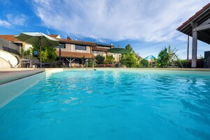 Una piscina al aire libre de temporada, sombrillas