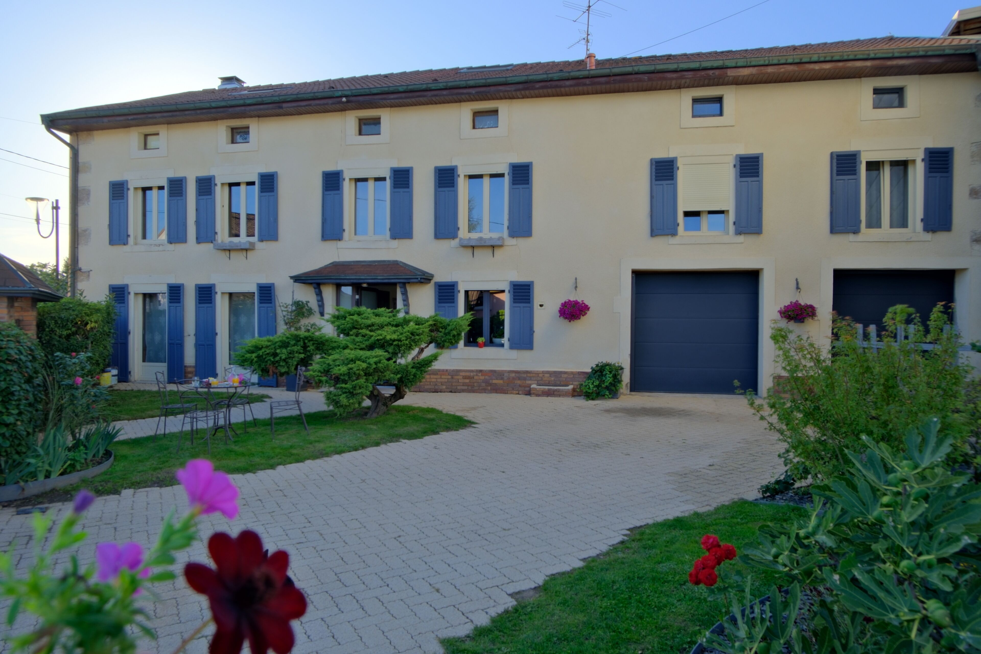 A two-story building with a paved driveway and a garden with flowers.