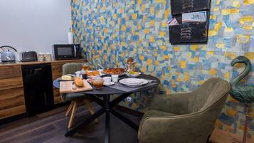 A dining area with a table set for breakfast, a microwave, a toaster, and a coffee machine.
