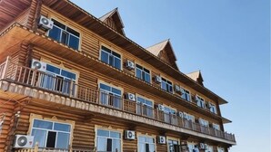 Un edifici de fusta de diversos pisos amb balcons, grans finestres i aparells d'aire condicionat.