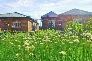 Wooden cabins with metal roofs, surrounded by a field of white flowers.