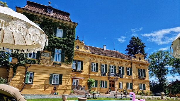 A large, yellow building with green shutters, a swimming pool, and outdoor seating. - Palais Kneissl (Burgau)