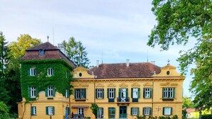 A large, yellow building with green shutters and a well-maintained lawn in front. - Palais Kneissl (Burgau)