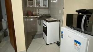 Cocina compacta con refrigerador, microondas, horno y alacenas.