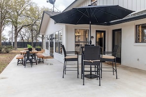 A patio with outdoor furniture, including a table and chairs, and a large umbrella.