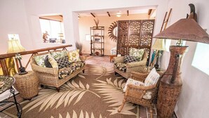 A living room with wicker furniture, a patterned rug, and a decorative wall panel. - Tropical retreat with beautiful pool and yard (San Miguel de Cozumel)