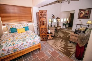 Une chambre à coucher avec un lit, une cloison en bois, une chaise, une lampe et un miroir.