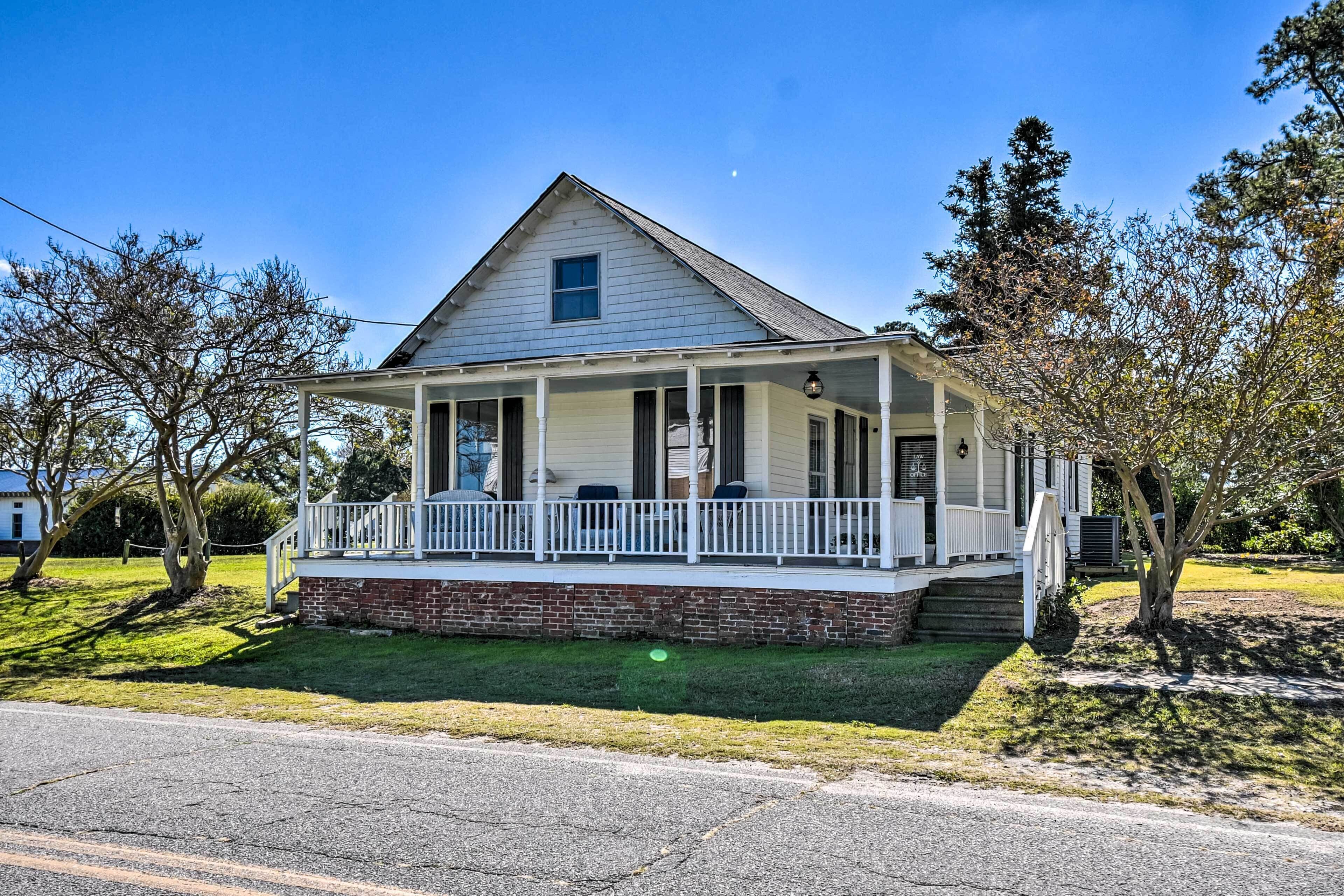 A single-story house with a porch, a brick foundation, and a clear blue sky.