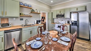 Una cucina moderna con mobili verdi, elettrodomestici in acciaio inossidabile e un'area pranzo con tavolo in legno apparecchiata per quattro persone.