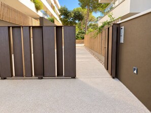 A corridor with a modern building on one side, a wooden fence on the other, and a clear sky. - Apartamento Nuevo, Equipado y Decorado con Estilo (Palamós)