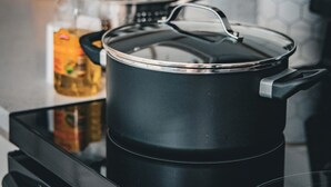 A kitchen with a stove, a pot, a bottle, and a set of knives on the counter. - Newly Updated 3BR Furnished Home Close to Path, Lightrail and Pets Welcome (Jersey City)