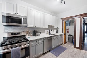 Enjoy cooking in this well-equipped kitchen with stainless steel appliances, a dishwasher, and white cabinetry.