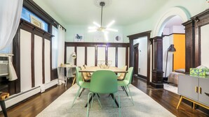 A dining area with a wooden table and green chairs, a ceiling fan, and a view of the adjacent room. - Newly Updated 3BR Furnished Home Close to Path, Lightrail and Pets Welcome (Jersey City)