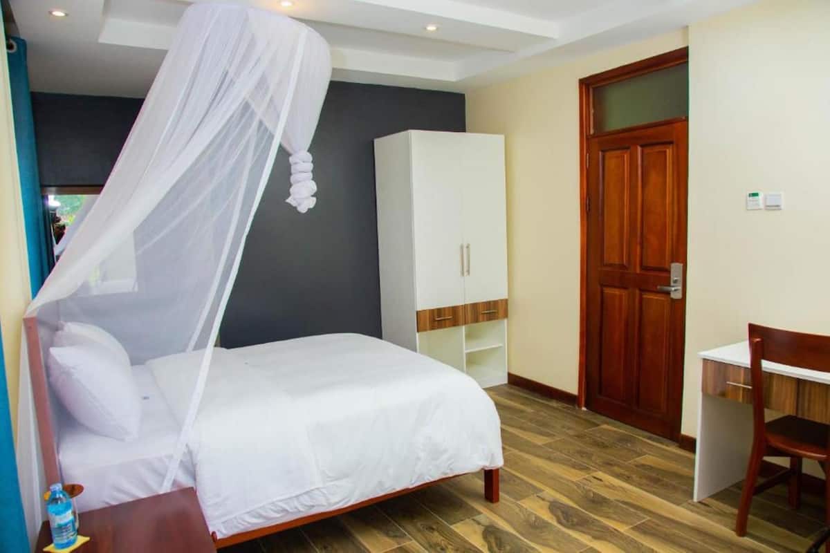 Un dormitorio con cama, armario, escritorio y puerta.