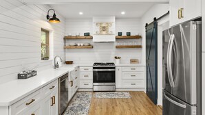 A modern kitchen with white cabinetry, a stainless steel refrigerator, and wooden flooring.