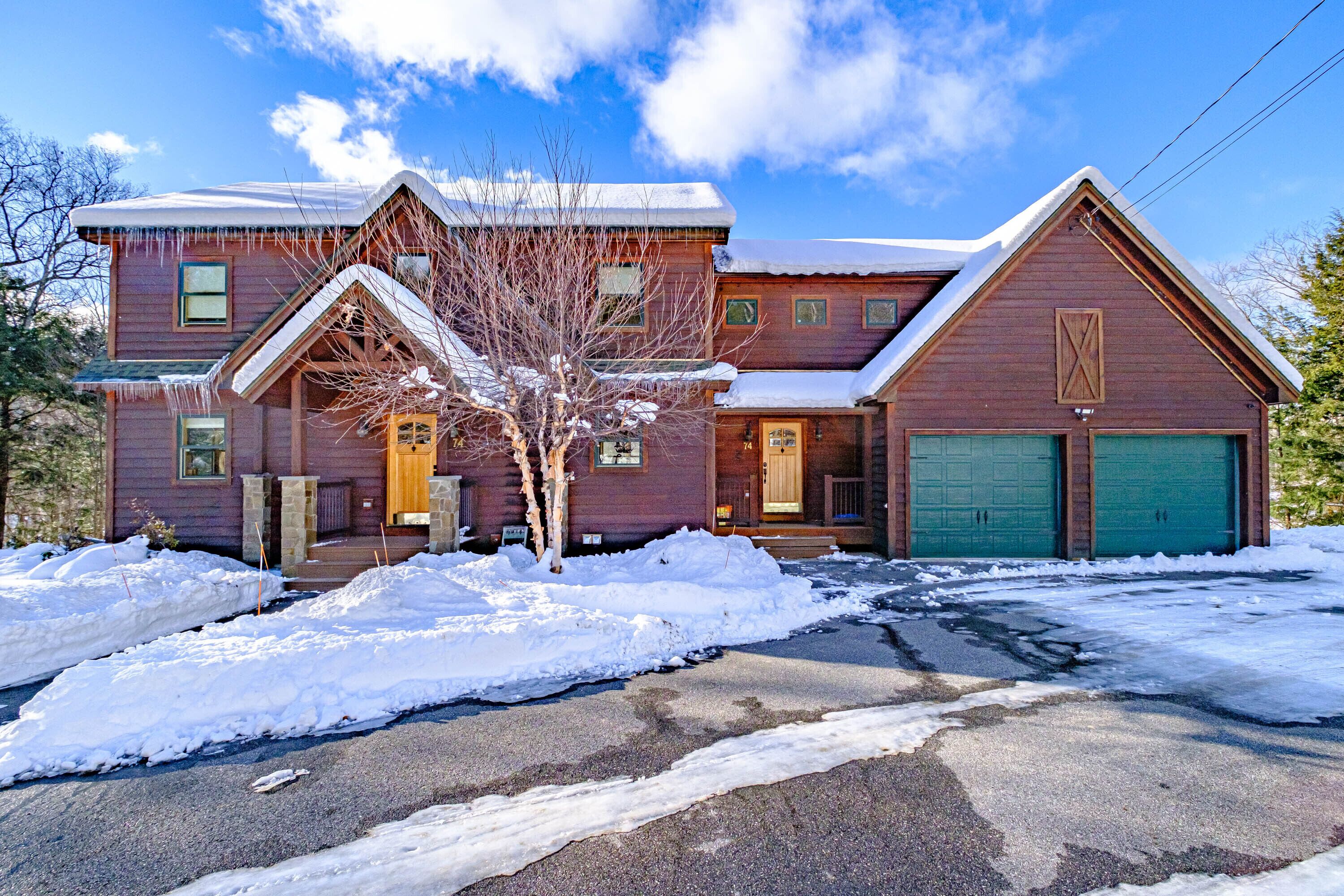A two-story wooden house with a snow-covered roof and driveway.