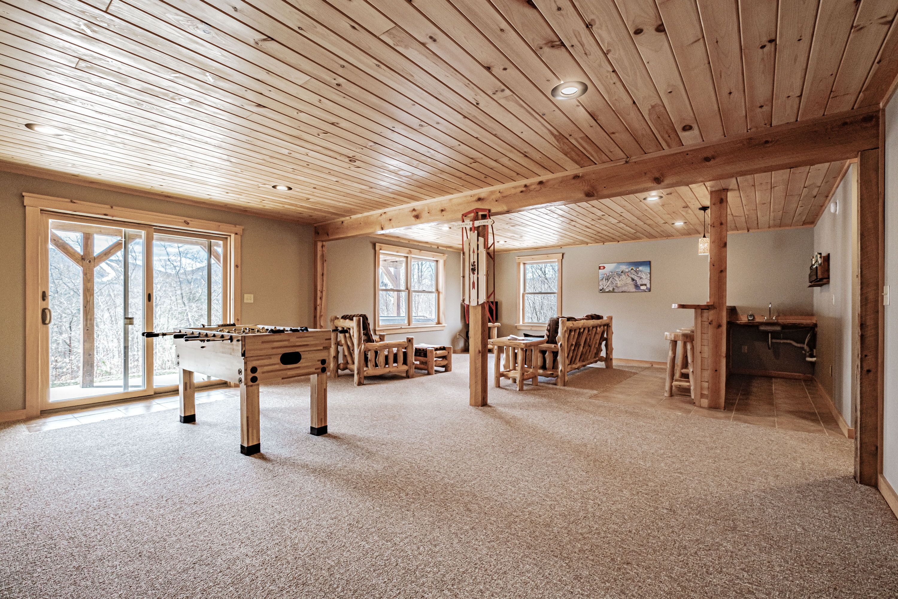 A spacious room with a wooden ceiling, a foosball table, and a kitchen area.