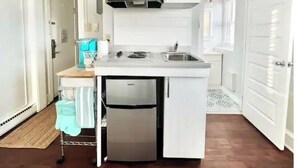 Een kleine keuken met witte kastjes, een inbouwfornuis en een koelkast.