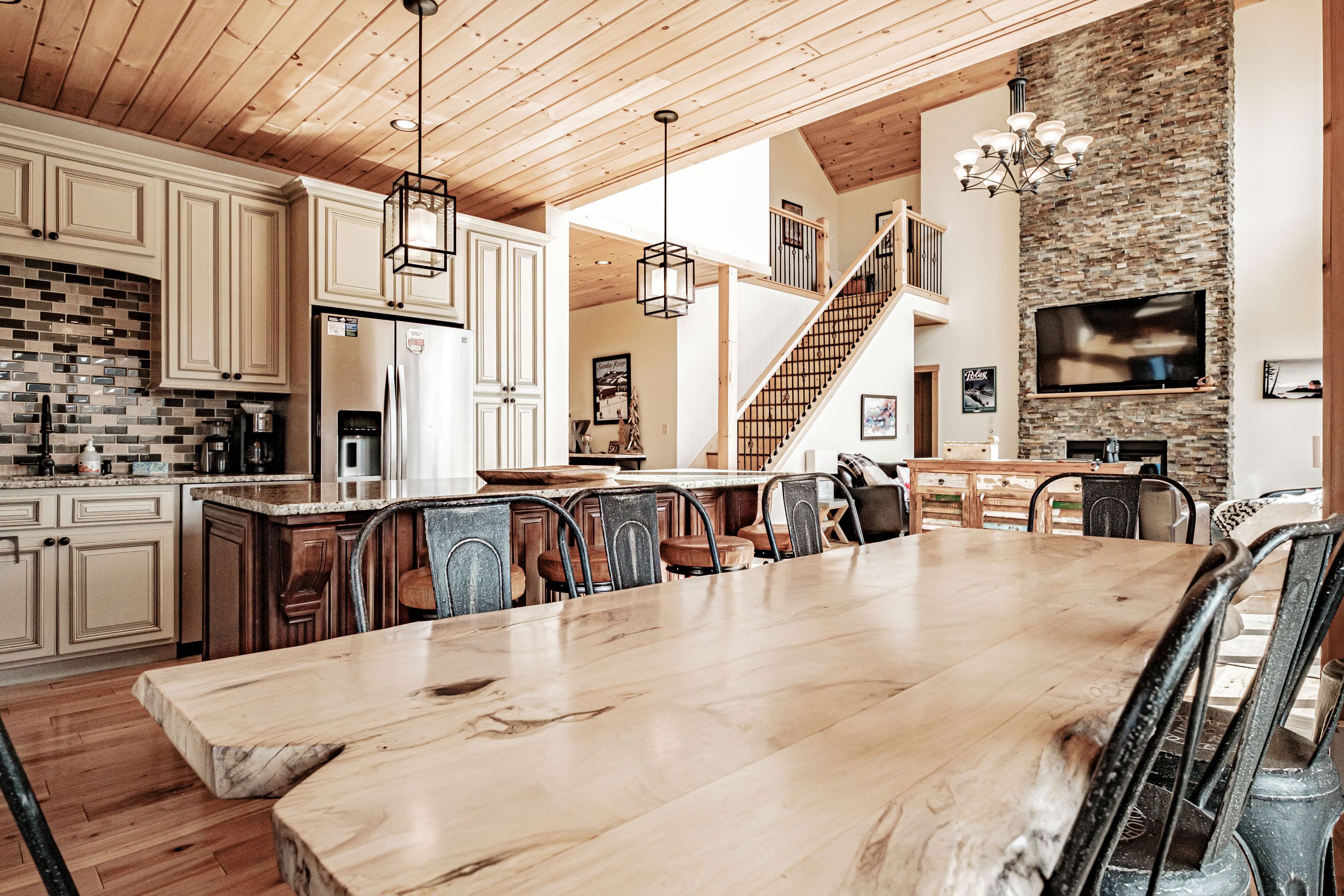 Una cocina amplia con armarios de madera, una isla grande y una pared decorativa de piedra.