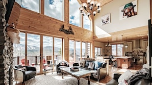 A spacious living area with a large window overlooking a mountainous landscape, a cozy seating area, and a modern kitchen. - 2 miles within Sunday river, mountain side house (Newry)