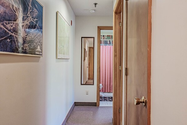A hallway with a wooden door, a mirror, and a framed picture on the wall. - On Mountain two bedroom unit sleeping 6 (Newry)
