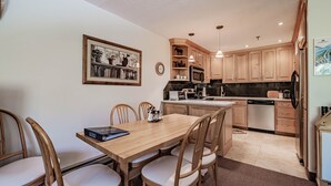 A modern kitchen with wooden cabinets, a dining table with chairs, a microwave, and a coffee maker. - On Mountain two bedroom unit sleeping 6 (Newry)