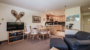 A living room with a TV, wooden furniture, a sofa, and a dining area with chairs and a table. - On Mountain two bedroom unit sleeping 6 (Newry)
