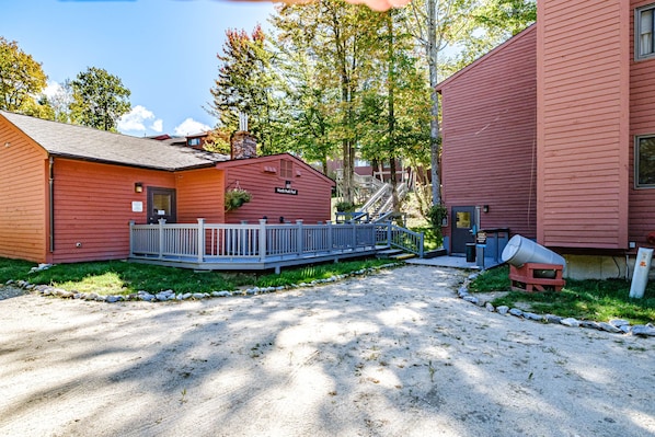 A red building with a deck and a staircase leading to a second level.