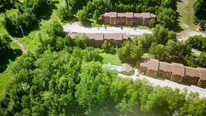 Vista aérea de un complejo residencial con varios edificios de apartamentos, una zona de estacionamiento y una piscina.