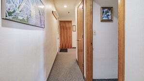 Un couloir doté d’un sol recouvert de moquette, de portes en bois et d’une carte encadrée accrochée au mur.
