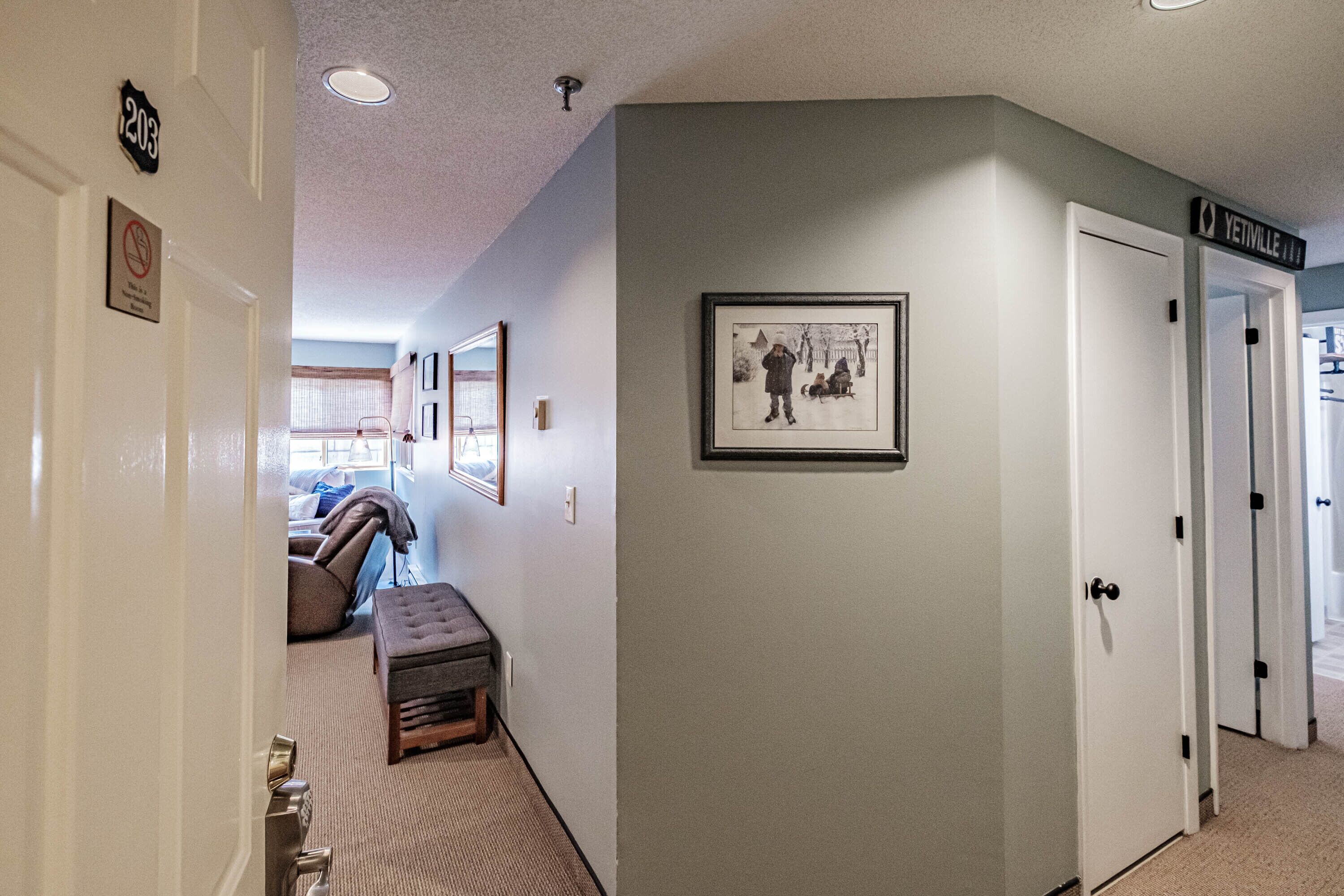A hallway with a bench, framed pictures, and a door labeled "YenVille."