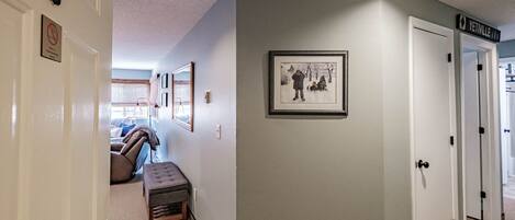 A hallway with a bench, framed pictures, and a door labeled "YenVille."