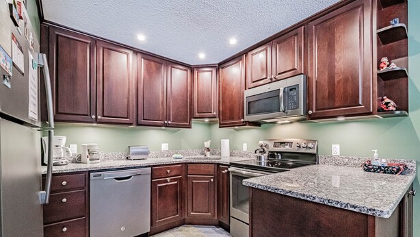 A kitchen with wooden cabinets, a microwave, a dishwasher, and granite countertops. - On Mountain two bedroom unit sleeping 6 (Newry)