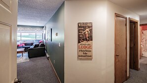 A hallway with a welcome sign, a couch, and a door. - On Mountain two bedroom unit sleeping 6 (Newry)