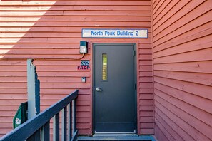 Un bâtiment rouge avec une porte noire, une enseigne indiquant « North Peak Building 2 » et une boîte aux lettres portant le numéro « 372 ».