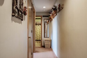 Enter a serene hallway with a door to a room featuring a window, a wicker basket, and a shelf with decorative items.