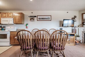 A kitchen with wooden cabinets, a microwave, a stove, and a dining area with four wooden chairs.