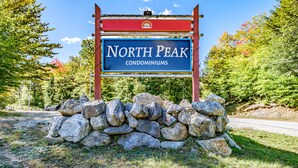 Une enseigne indiquant le complexe d’appartements North Peak, avec un mur de pierres en façade.