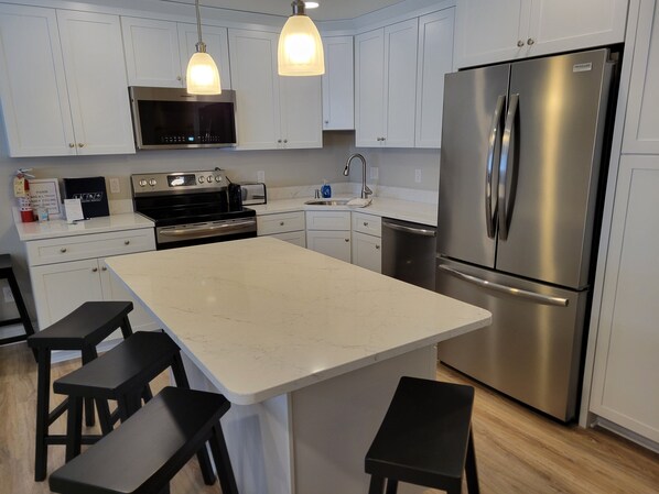 A modern kitchen with white cabinets, a stainless steel refrigerator, a built-in oven, a microwave, and pendant lighting. - On Mountain two bedroom unit sleeping 8 (Newry)