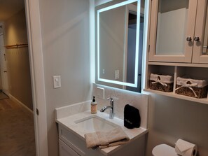A bathroom with a white sink, a mirror, a towel, and a toilet. - On Mountain two bedroom unit sleeping 8 (Newry)