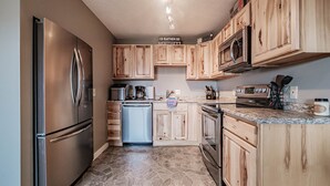 A kitchen with wooden cabinets, a stainless steel refrigerator, a dishwasher, a microwave, and a stove.