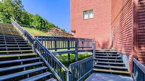 Een aantal houten trappen met metalen leuningen leiden naar een rood gebouw.