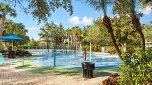 A pool area with a water slide, lounge chairs, and a trash bin. - Cheerful Condo - minutes away from Disney/ with Pools, Resturant & Spa (Davenport)