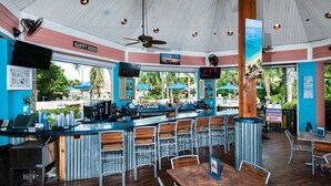 An indoor bar area with a high ceiling, bar counter, seating, and outdoor view. - Cheerful Condo - minutes away from Disney/ with Pools, Resturant & Spa (Davenport)