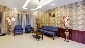 A living room with a stone wall, two blue sofas, a coffee table, and decorative vases. - Itsy Hotels Regalia Grand, 500 Mtrs From Madikeri Fort (Madikeri)