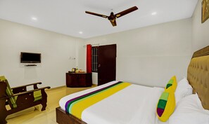 A hotel room with a bed, a desk, a chair, a television, and a ceiling fan.