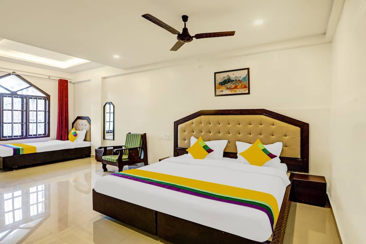 A hotel room with a large bed, a chair, a ceiling fan, and a window with curtains.